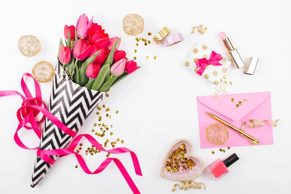 Pembe ve altın tarz Masası çiçekler ile. Siyah ve beyaz şık ambalaj kağıdı, hediyeler, kozmetik ve beyaz zemin üzerine konfeti ile kadın Aksesuarları Pembe Laleler