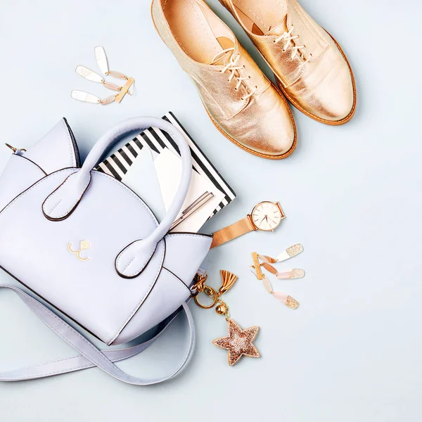 Cute blue ladies bag, stylish golden shoes and  feminine accessories . Flat lay, top view. Spring fashion concept in pastel colored