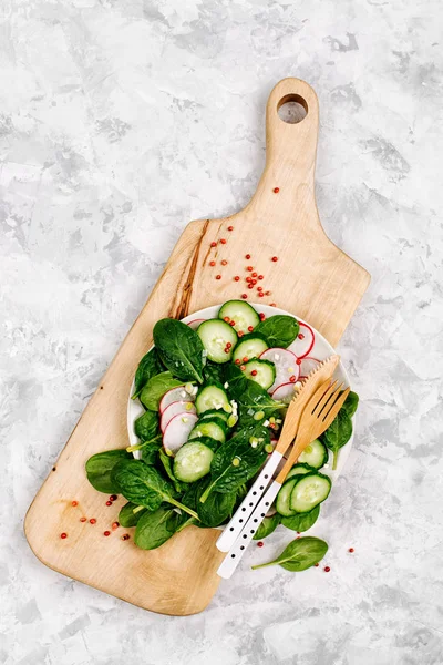 salad with cucumbers in cutting board on white background, top view