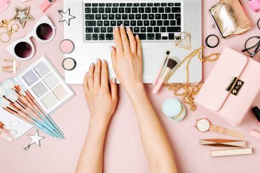 Moda blogger laptop ile çalışma. Kadın Aksesuar, kozmetik ürünleri soluk pembe tablo ile çalışma alanı. düz yatıyordu, en iyi görünümü