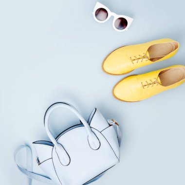 Güzel mavi bayan çanta, güneş gözlüğü ve şık sarı ayakkabı. Bahar moda kavramı