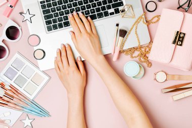 Moda blogger laptop ile çalışma. Kadın Aksesuar, kozmetik ürünleri soluk pembe tablo ile çalışma alanı. düz yatıyordu, en iyi görünümü