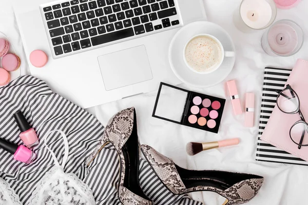 Fashion blogger workspace with laptop and woman accessories in bed. Flat lay, top view