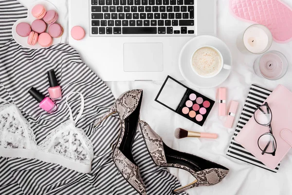 Fashion blogger workspace with laptop and woman accessories in bed. Flat lay, top view