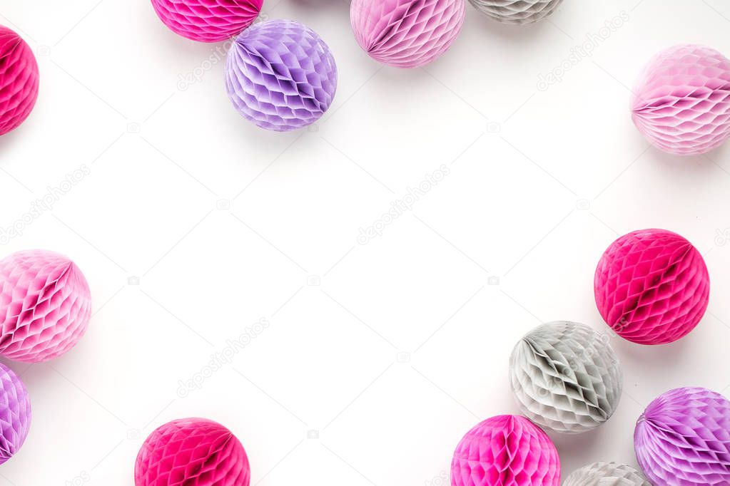 Manycolored decorative paper balls on white surface, top view, copy space