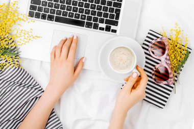 Genç kadın serbest meslek yatakta dizüstü bilgisayar ile çalışma.