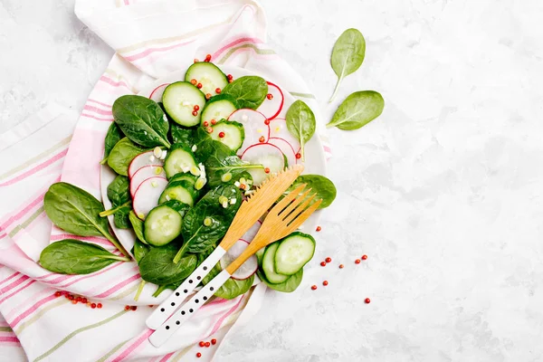 生蔬菜沙拉配切片黄瓜 菠菜叶和粉红色胡椒粉 配有时尚餐具的白色盘子 — 图库照片
