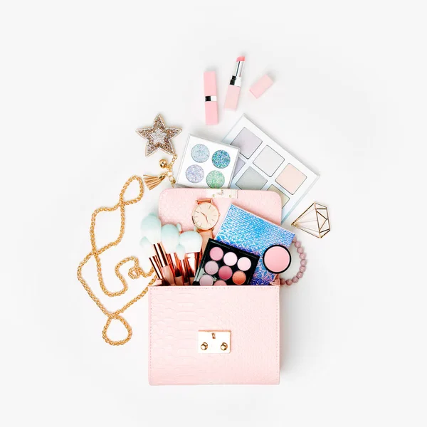 Cosmetic products flowing from makeup bag on white background.