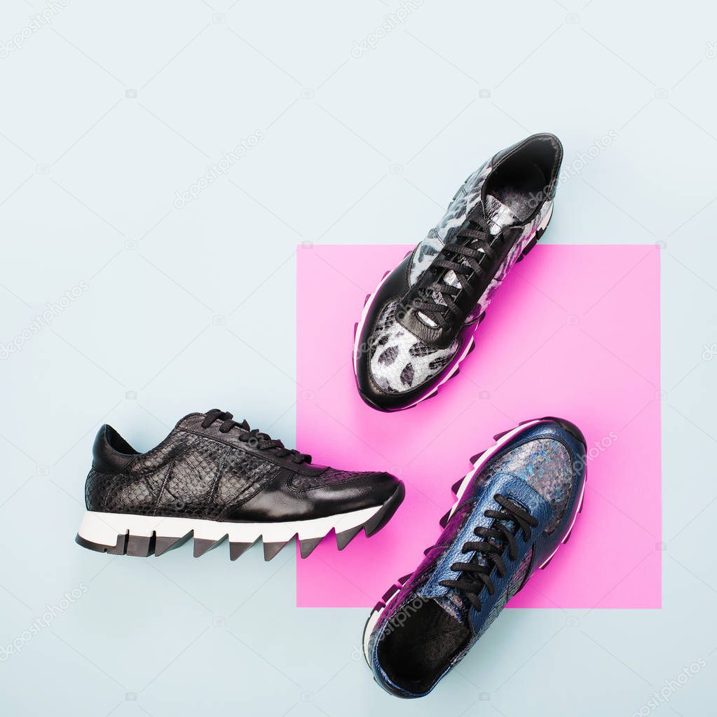 Stylish various sneakers on green and pink background