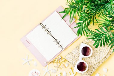 Tropikal yaprak, güneş gözlüğü, defter ve Sarı zemin üzerine kabukları ile plaj çantası.