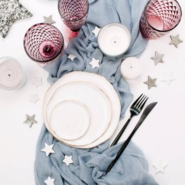 Beyaz tabaklar, pembe cam, siyah çatal bıçak takımı, gri kumaş, yıldız ve beyaz arka plan üzerinde izole kalp bileşimi