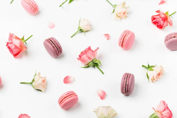 Seamless background with macaroons and roses isolated on white background