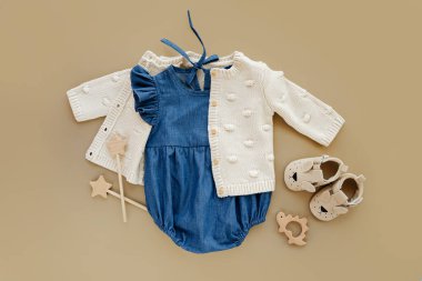 Knitted  jumper  with Blue romper and shoes. Set of baby clothes and accessories for little girl on beige background.  Fashion newborn. Flat lay, top view