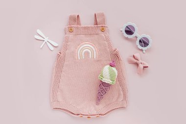 Pink knitted bodysuit with toy ice cream and sunglasses. Set of baby clothes and accessories summer. Fashion newborn. Flat lay, top view
