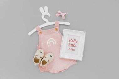 Pink knitted bodysuit on cute hanger with bunny ears with photo frame and baby boots. Set of kids clothes and accessories summer. Fashion newborn. Flat lay, top view