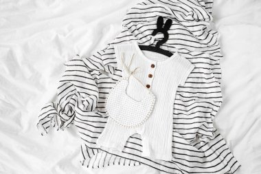 White romper and  bib on striped blanket. Set of  kids clothes and accessories for summer  on bed. Fashion childs outfit. Flat lay, top view