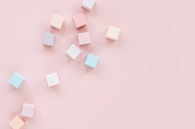 Colorful wooden toy blocks. Stylish baby toys on pastel pink background. Eco friendly, plastic free toys accessories for kids. Flat lay, top view
