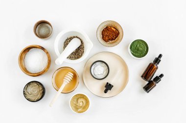 Beauty treatment ingredients for making homemade skin care cosmetic mask. Various bowl with clay, cream, essential oil and natural ingredients  on white table background. Organic spa cosmetic products