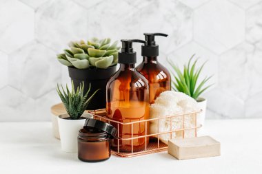 Banyo aksesuarları, doğal kozmetik ürünleri ve araçları ile yeşil bitki ile beyaz masa üzerinde bir banyo arka plan içinde.
