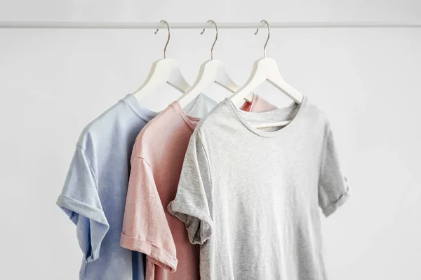 T-Shirts in pastel color on hanger on white background. Basic female clothes. Spring/summer outfit.