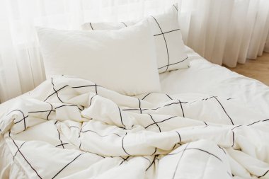 Çizgili battaniye ve yastık ile beyaz yatak çarşafları. Dağınık yatak. 