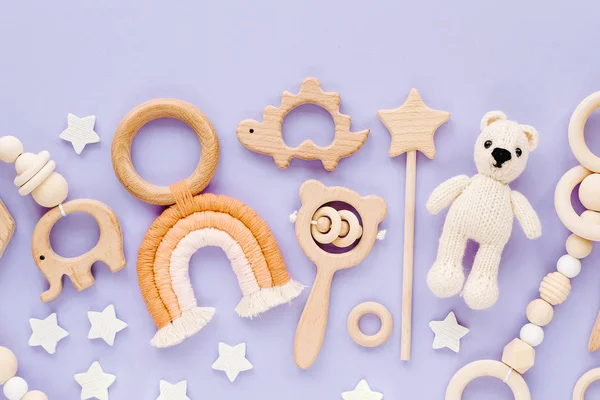 Cute wooden baby toys on light-blue background. Knitted bear, rainbow, dinosaur toy, beads and stars. Eco accessories,  beanbag and teethers for newborn. Flat lay, top view