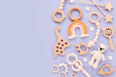 Cute wooden baby toys on light-blue background. Knitted bear, rainbow, dinosaur toy, beads and stars. Eco accessories,  beanbag and teethers for newborn. Flat lay, top view