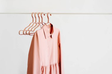 Pale pink dress with metallic hangers  on white background. Elegant   fashion outfit. Spring wardrobe. Minimal concept.