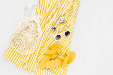 Yellow dress with stripes with slippers, sunglass, and white  eco bag . Women's stylish summer outfit. Trendy clothes. Flat lay, top view.
