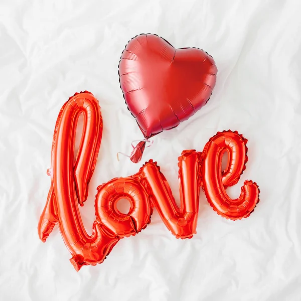 Μπαλόνια Red Air Σχήμα Της Λέξης Αγάπη Καρδιές Στο Κρεβάτι — Φωτογραφία Αρχείου
