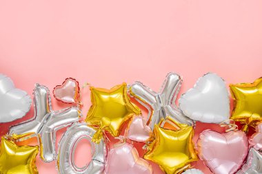 XO foil balloon letters and air balloons of heart shaped and stars. Love concept. Holiday and celebration. Valentine's Day or wedding/bachelorette party decoration. Colorful Metallic air balloons on pink background.