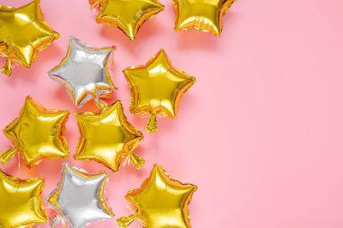 Gold and silver foil balloons of star shaped on pink background. Holiday and celebration concept. Birthday Day or party decoration. Metallic air balloons. Congratulation. Greeting card. 