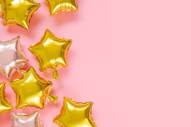 Gold and silver foil balloons of star shaped on pink background. Holiday and celebration concept. Birthday Day or party decoration. Metallic air balloons. Congratulation. Greeting card. 