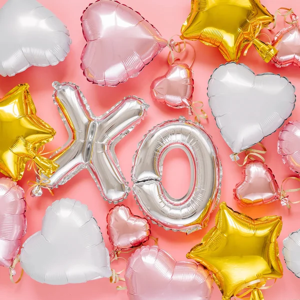 XO foil balloon letters and air balloons of heart shaped and stars. Love concept. Holiday and celebration. Valentine\'s Day or wedding/bachelorette party decoration. Colorful Metallic air balloons on pink background.