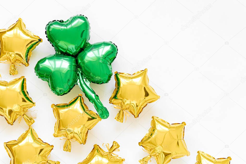 St.Patrick 's Day party decoration. Gold foil balloons of stars shapes and green balloons of clover leaf shaped. Holiday and celebration concept. Metallic air balloons.