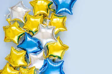 Gold and silver foil balloons of star shaped on blue background. Holiday and celebration concept. Birthday Day or party decoration. Metallic air balloons. Congratulation. Greeting card. 