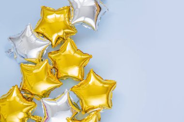 Gold and silver foil balloons of star shaped on blue background. Holiday and celebration concept. Birthday Day or party decoration. Metallic air balloons. Congratulation. Greeting card. 