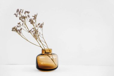 Branch flowers in a glass vase on white table. Decor for interior. Stylish decoration for home.