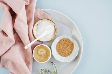 Beauty treatment ingredients for making homemade skin care cosmetic mask. Various bowl with clay, cream, essential oil and natural ingredients  on white table background. Organic spa cosmetic products