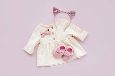Pembe ayakkabılı beyaz elbise. Pastel arka planda bahar ya da yaz için bebek kıyafetleri ve aksesuarları. Moda çocuk kıyafeti. Düz yatış, üst görünüm