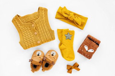 Yellow knitted romper, hairband, socks and cute baby slippers.  Set of newborn clothes and accessories. Flat lay, top view  clipart