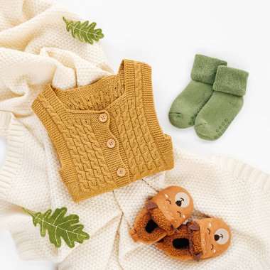 Sarı tulum, çoraplar ve örgü battaniyeli şirin bebek terlikleri. Yeni doğan kıyafetleri ve aksesuarlar. Düz yatış, üst görünüm 