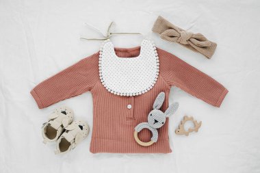 Yeni doğan bebek için beyaz battaniyeye bağlanmış oyuncak tavşanlı örgü, önlük ve saç fiyonku. Bebek eşyaları ve aksesuarlar. Düz yatış, üst görünüm