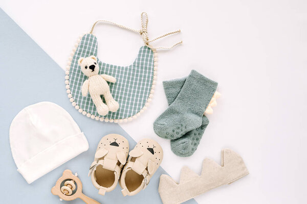 Bib,  socks, toy and cute baby slippers for boy.  Set of  newborn clothes and accessories. Flat lay, top view 