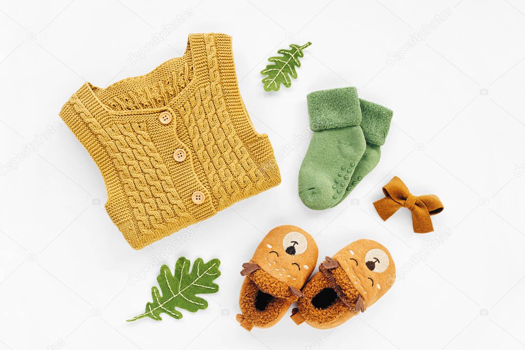 Yellow knitted romper,  socks and cute baby slippers.  Set of  newborn clothes and accessories. Flat lay, top view 