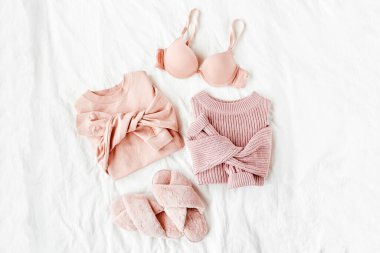 Beyaz levha üzerinde sütyen ve kabarık kürk terlik ile soluk pembe sıcak kazak. Kadın şık giysi kolaj. Düz döşeme, üst görünüm. 