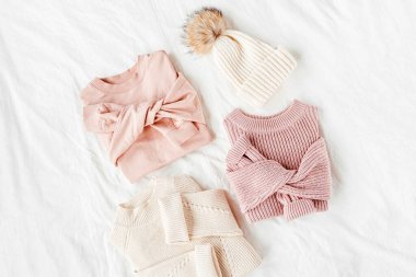 Üç soluk pembe ve beyaz sıcak kazak ve yatakta kışlık şapka. Kadın şık giysileri. Rahat Kış bakmak. Düz döşeme, üst görünüm.
