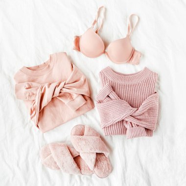 Beyaz levha üzerinde sütyen ve kabarık kürk terlik ile soluk pembe sıcak kazak. Kadın şık giysi kolaj. Düz döşeme, üst görünüm. 