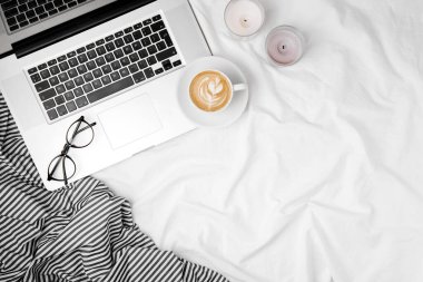 Laptop ve kahveyle yatakta çalışma alanı. Sabah konsepti. Düz yatıyordu 
