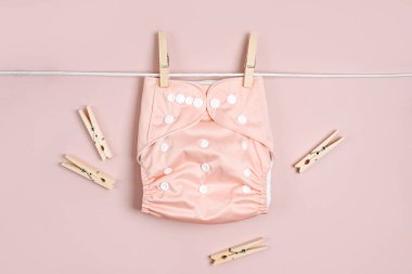 Yeniden kullanılabilir bez bebek bezleri çamaşır ipinde kuruyor. Pembe arka planda çevre dostu bezler. Sürdürülebilir yaşam tarzı. Sıfır atık.